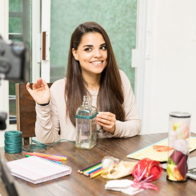 Portrait of a pretty young female crafts blogger greeting her audience on video while working on a project